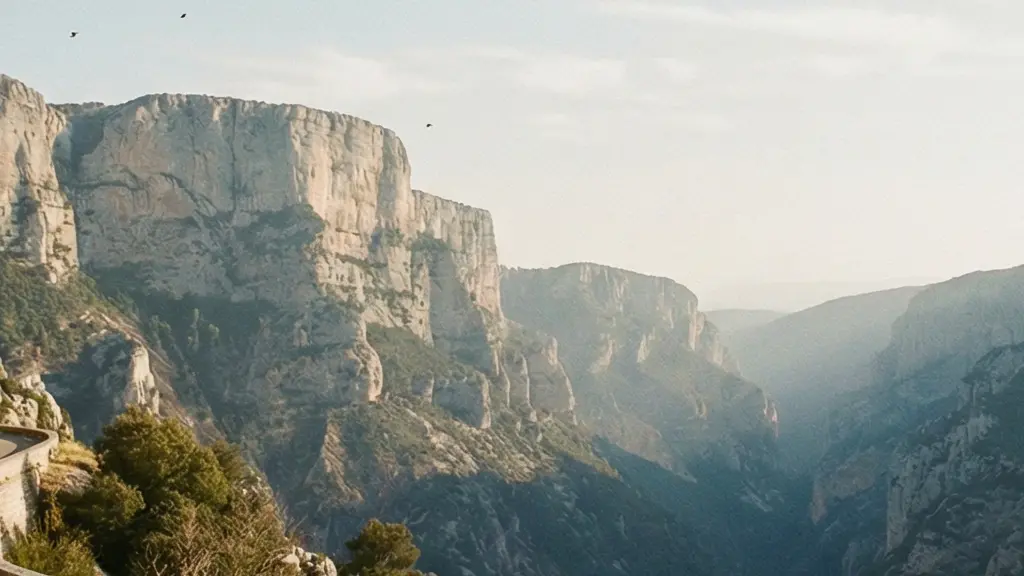 Plan très large d'un cycliste sur une route panoramique des gorges du Verdon, avec de grandes falaises au loin et un vaste ciel vide.