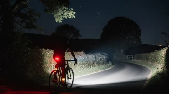 Cycliste avec éclairage LED sur route de campagne non éclairée sous ciel étoilé