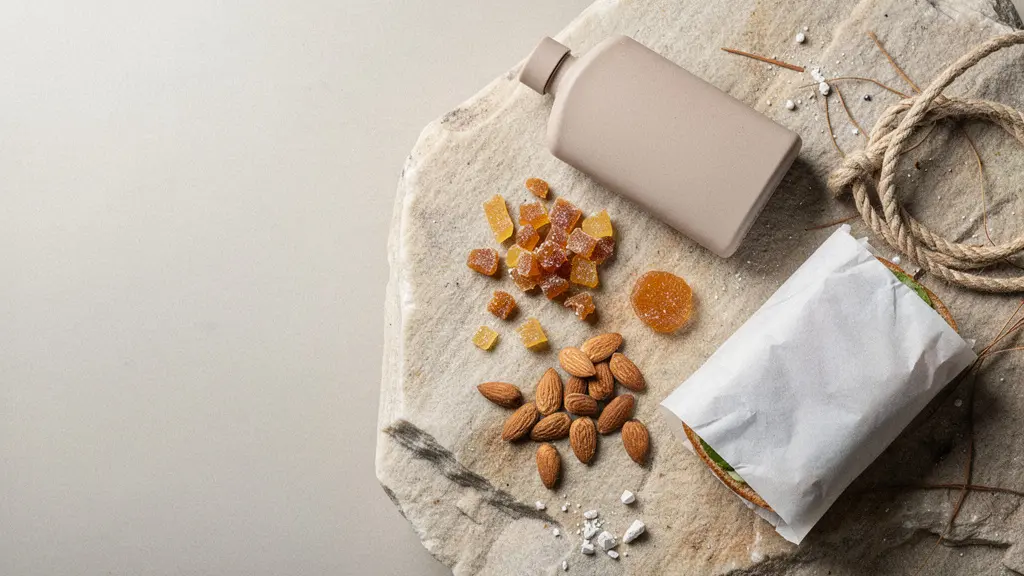 Gros plan sur un kit de nourriture de paroi posé sur du calcaire : amandes, pâtes de fruits, petite compote, barre énergétique et gourde, avec textures très nettes.