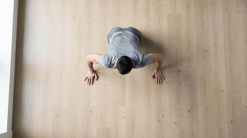 Vue aérienne d'une personne en position de pompe montrant l'angle de 45 degrés des coudes formant une flèche avec le corps